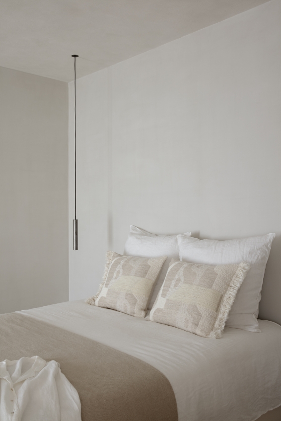 Helles, minimalistisch gestaltetes Schlafzimmer mit hochwertigen Betttextilien, strukturierten Zierkissen und natürlichen Stoffen als Beispiel für textile Innenarchitektur und Textile Interior Architecture von Die Stoffmacher in Stuttgart, Baden-Württemberg.