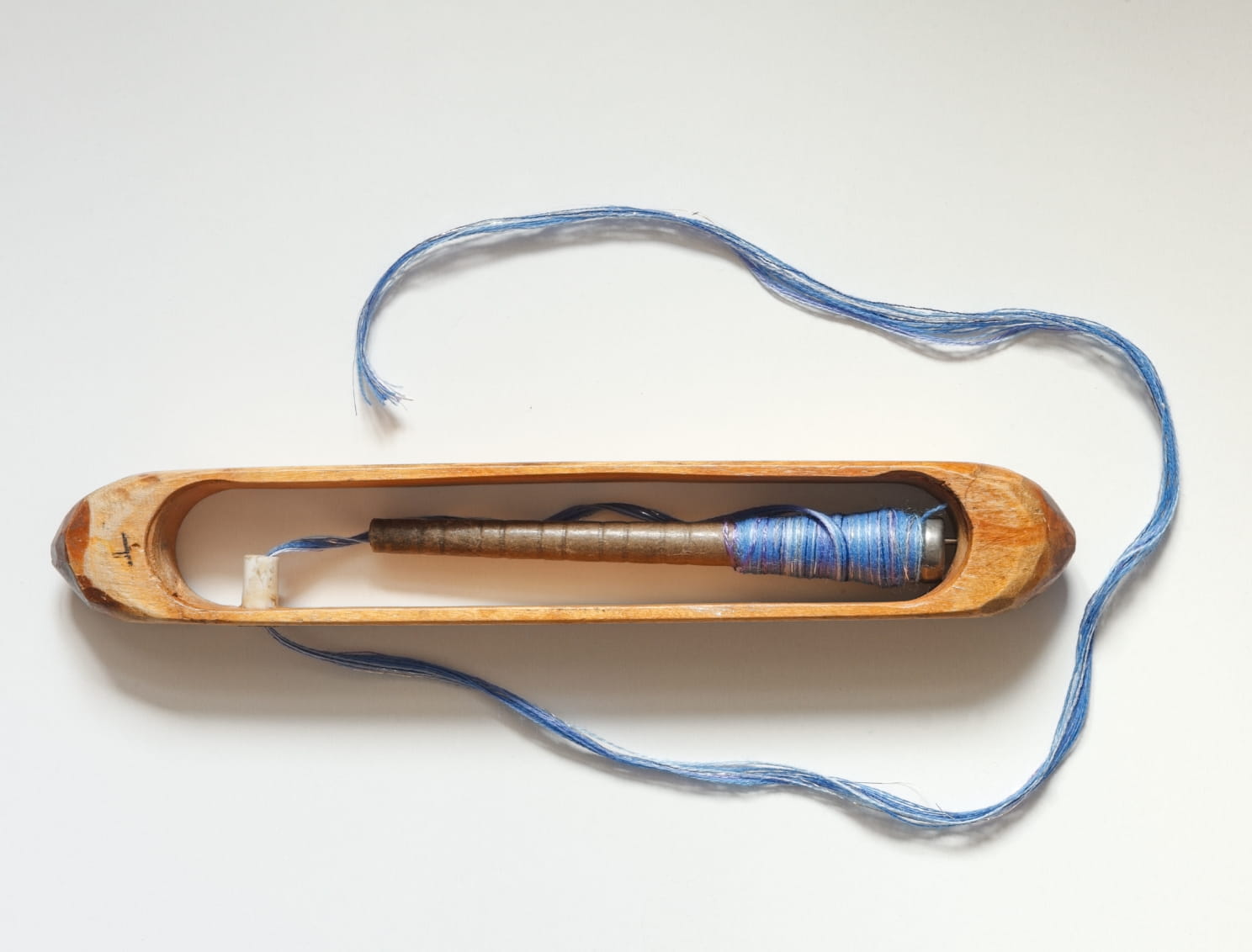 Traditional weaving shuttle with yarn by Die Stoffmacher from Baden-Württemberg as a symbol of custom fabric development in European weaving mills and manufactories.